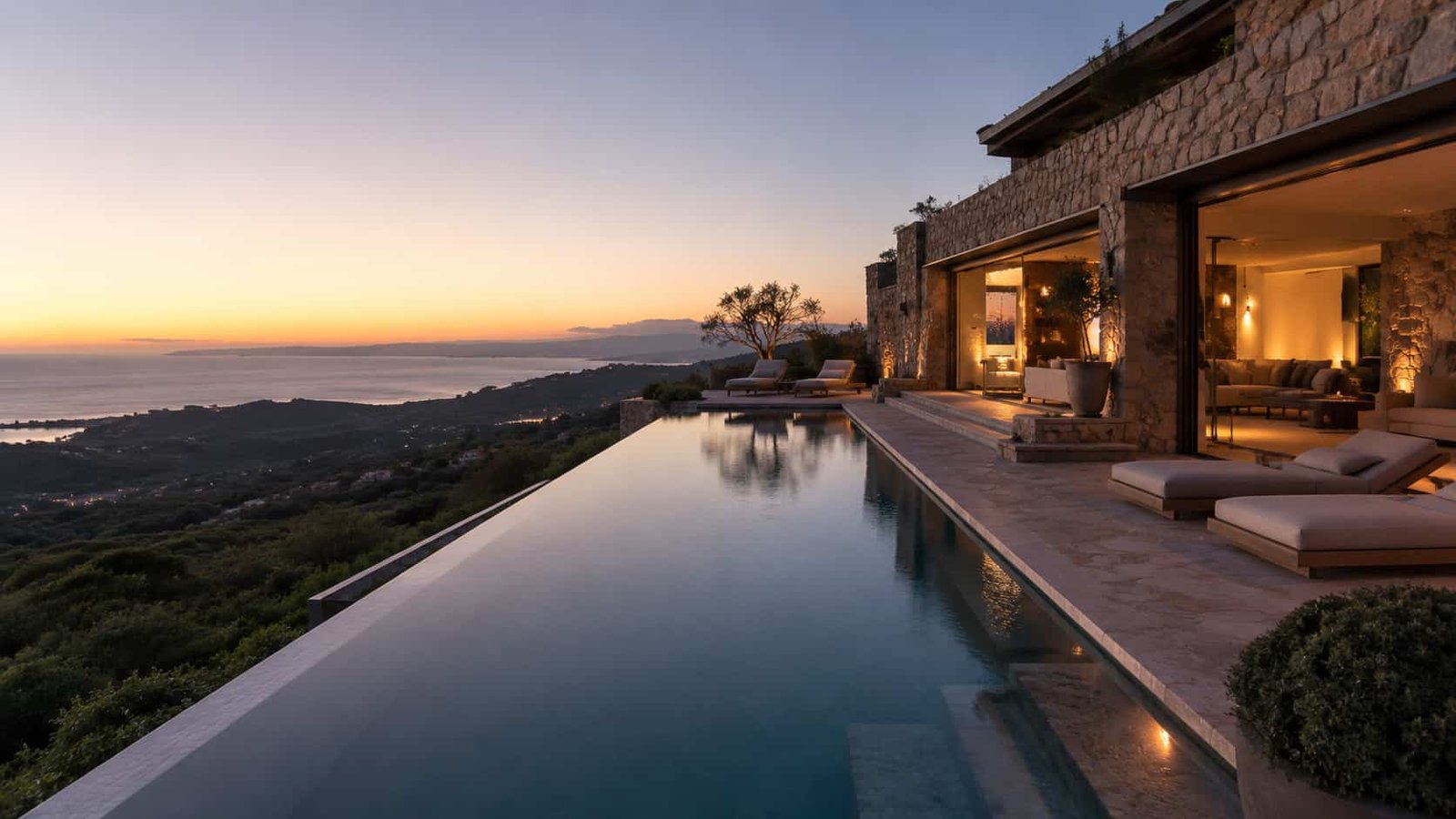 Exklusive private Villa mit Infinity-Pool, Naturstein, warmem Abendlicht und diskretem Blick in eine ruhige Landschaft.