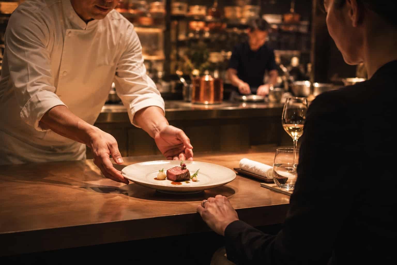 Intimer Moment am Chefs Counter, bei dem ein fein angerichteter Teller direkt vor einem Gast serviert wird.