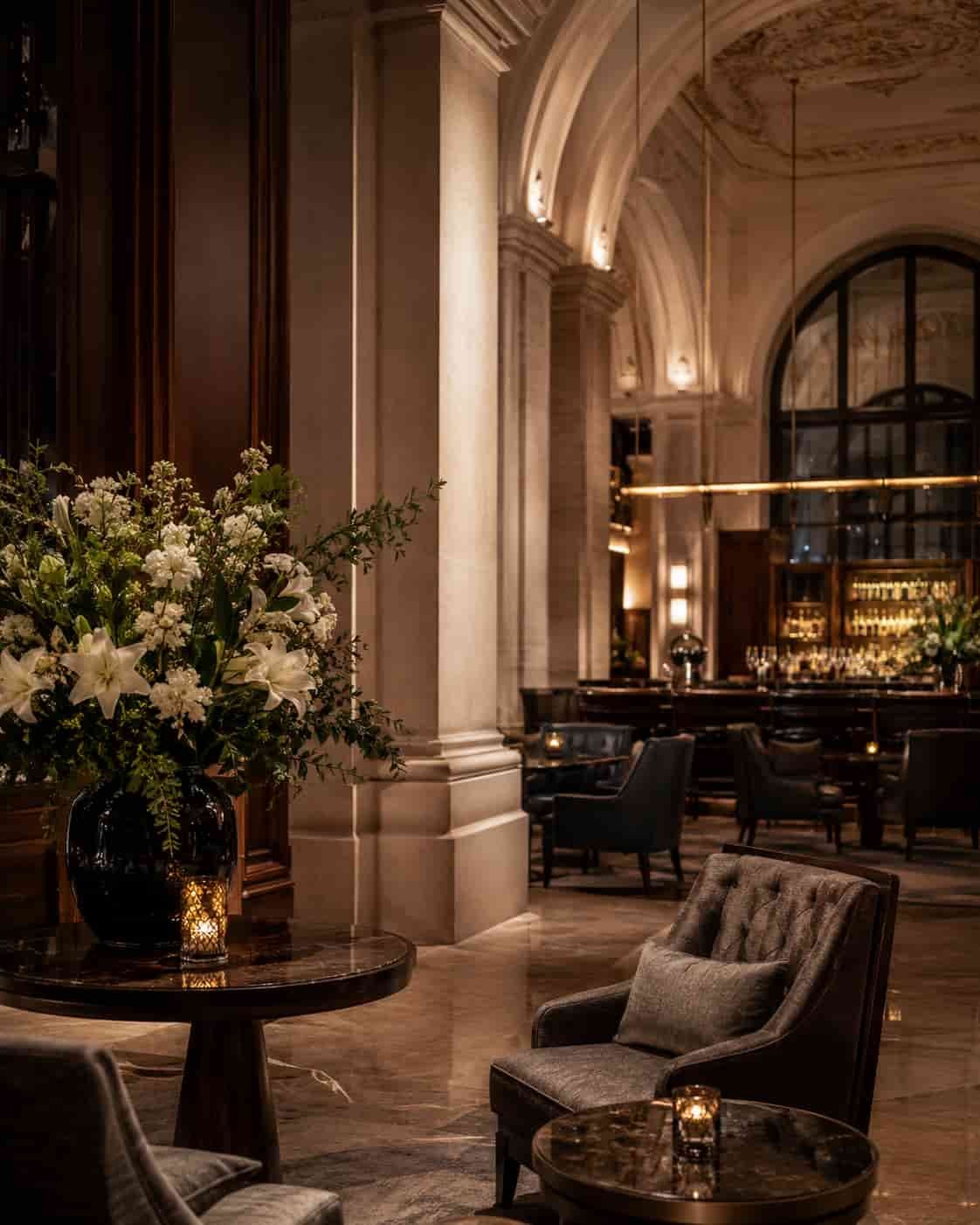Elegante Grand-Hotel-Lobby mit Naturstein, dunklem Holz, warmem Licht und kultivierter Atmosphäre als Symbol für klassischen urbanen Luxus.