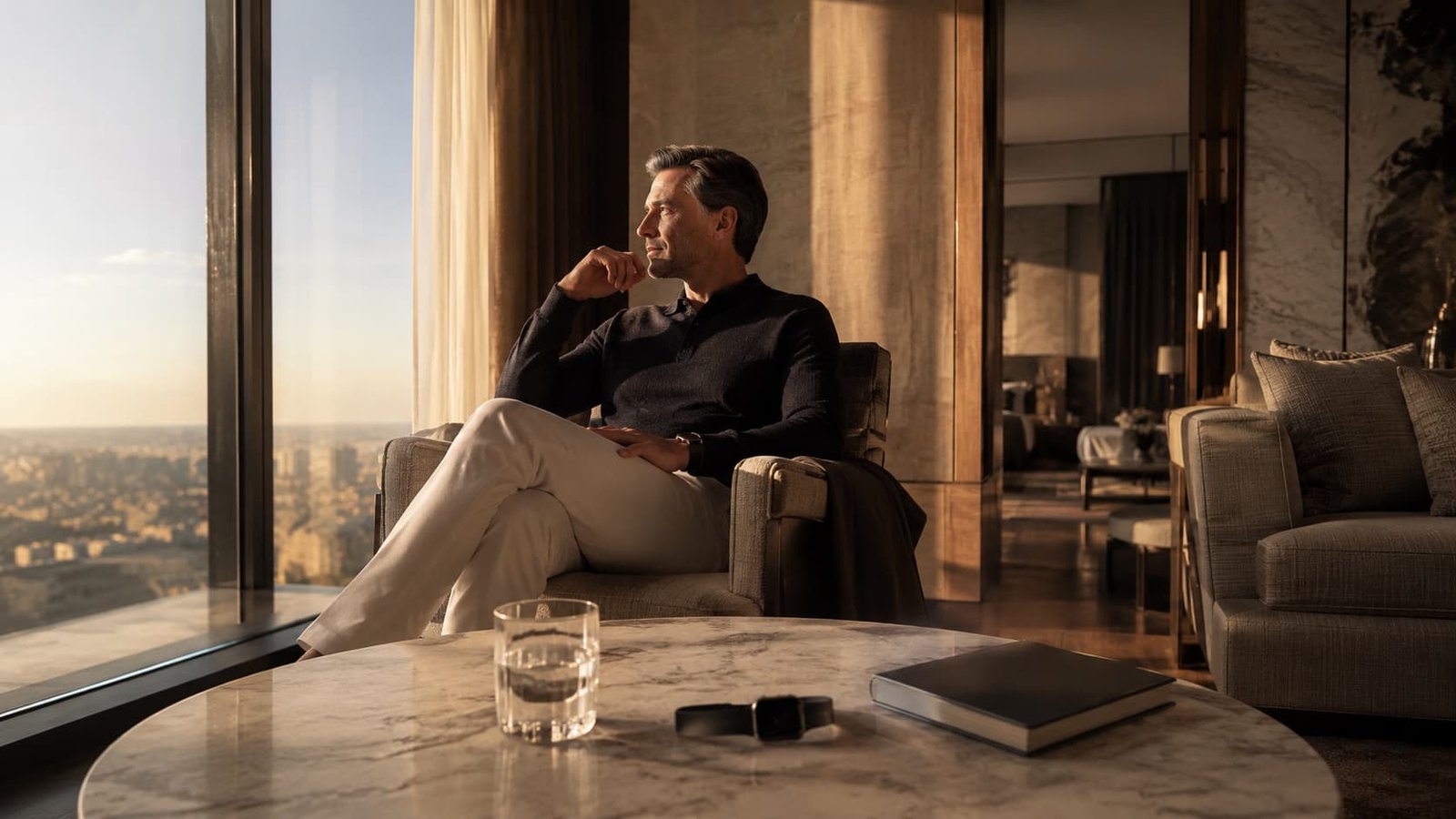 Luxuriöser Morgenmoment in einer privaten Suite mit ruhiger Longevity-Atmosphäre, Glas Wasser, Notizbuch und dezentem Wearable.